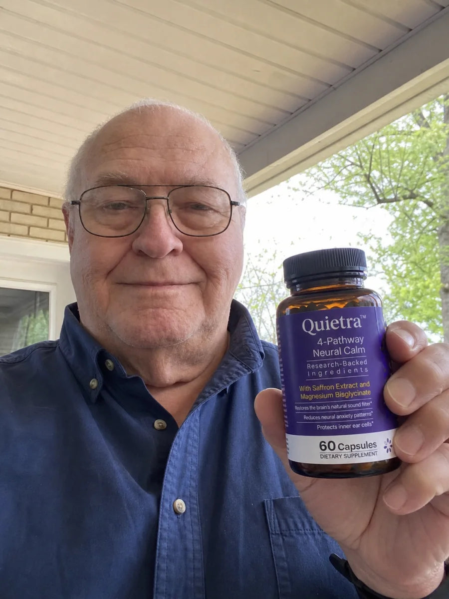 Man holding a bottle of Quietra on his porch