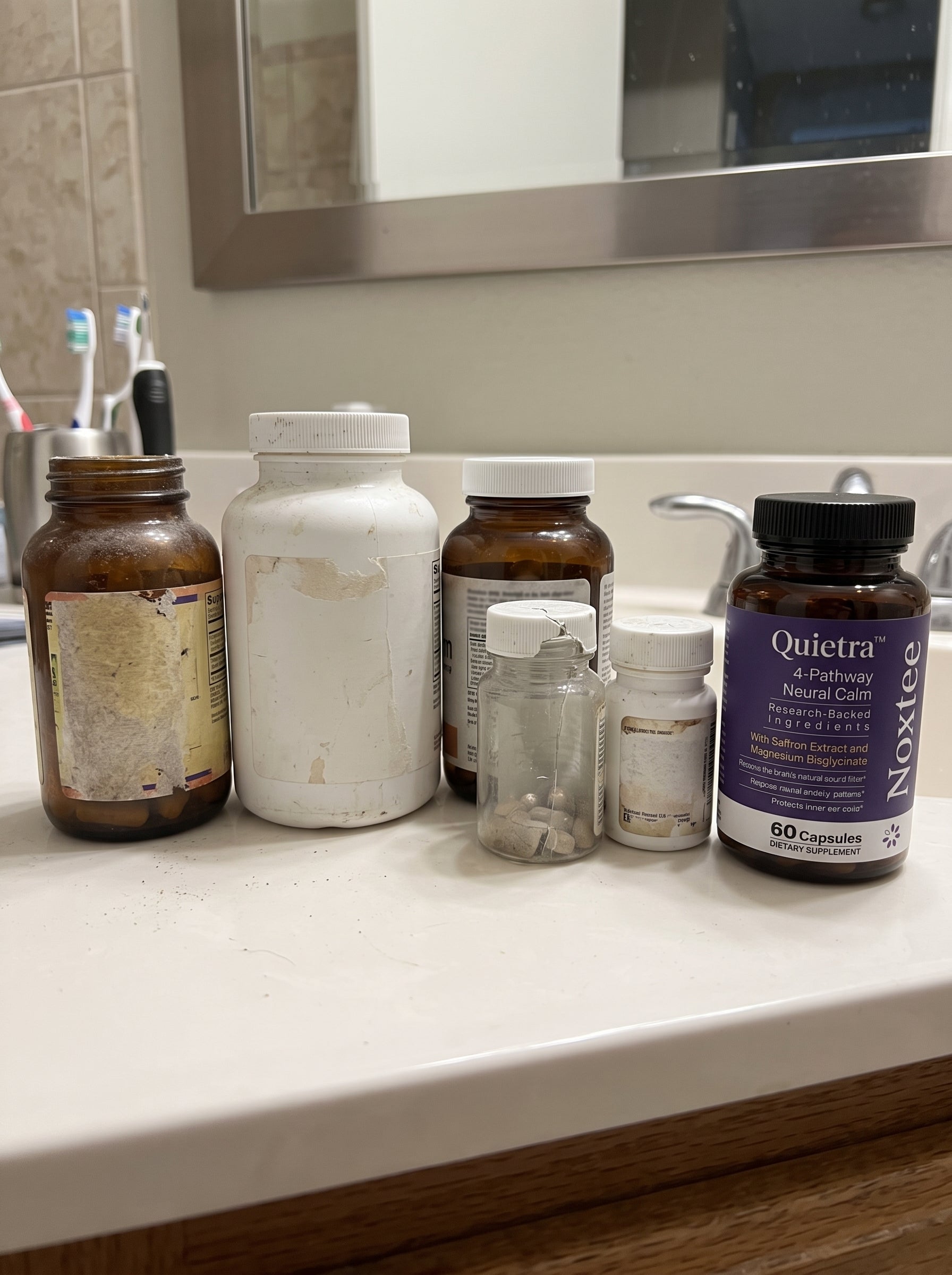 Old supplement bottles lined up beside a Noxtee bottle
